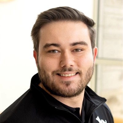 Kolton Tebbey, shoulders-up portrait in a black quarter-zip against a light background.